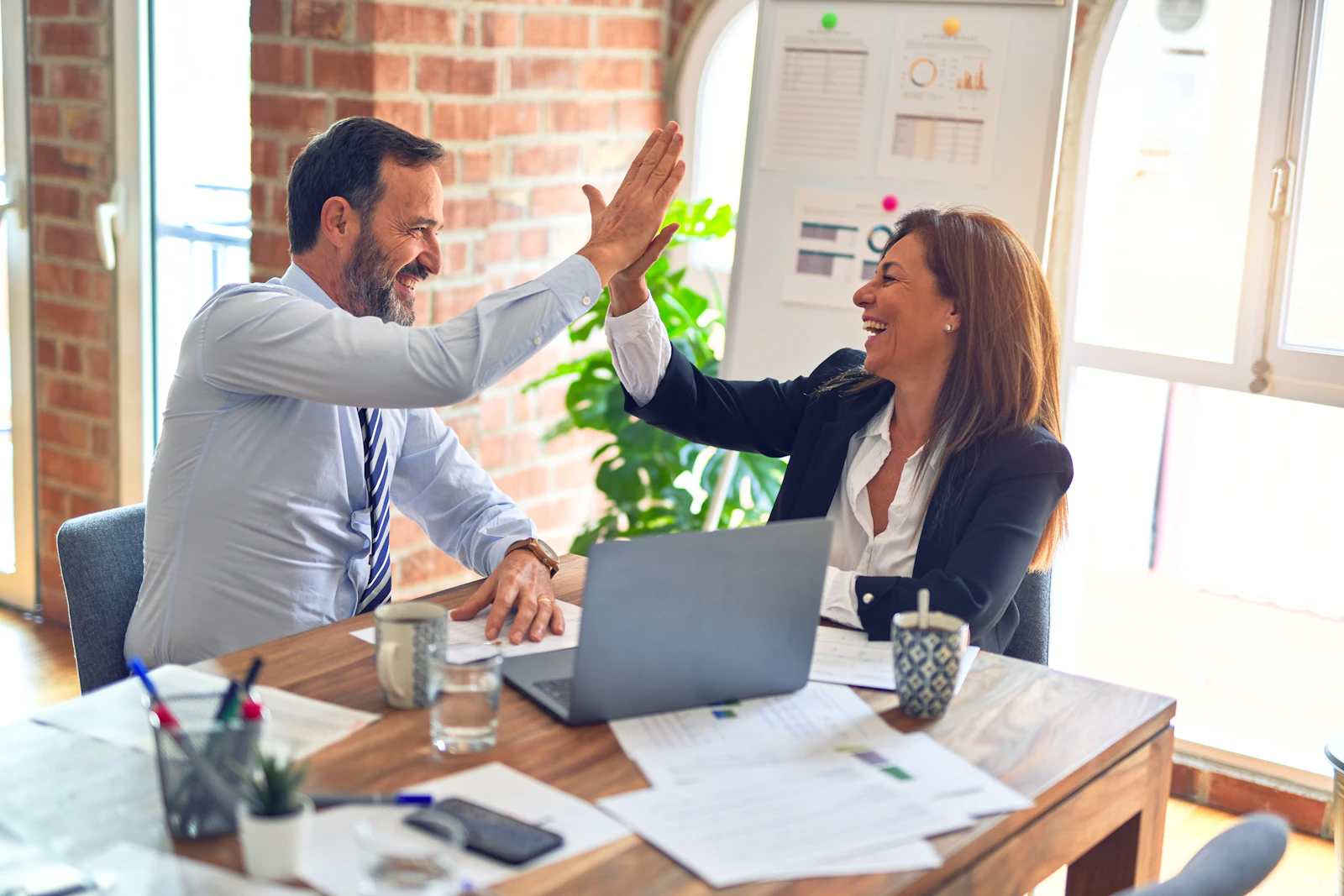 Two professionals celebrating a closed opportunity at a desk